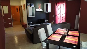 A modern living room with a sofa, a dining table with placemats, a flat-screen TV, and a wall-mounted cabinet. - Provvidenza (Motovun)