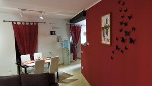A room with a red wall, a dining area with a table and chairs, a water dispenser, and a sofa. - Provvidenza (Motovun)