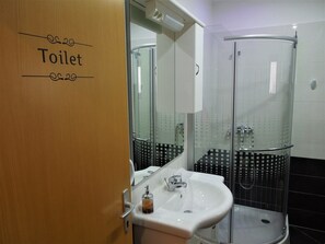 Un baño con inodoro, lavamanos y cabina de ducha de vidrio.