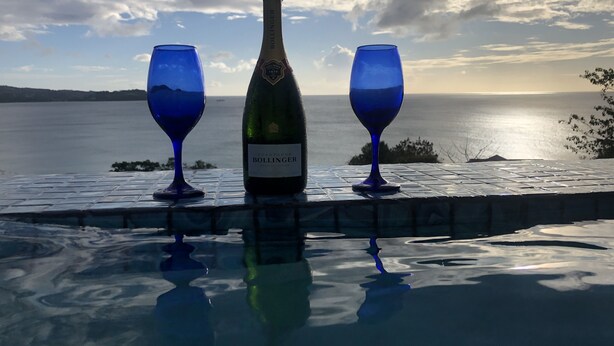 A bottle of Bollinger champagne and two blue wine glasses on a reflective surface with a view of the sea and sky. - Tropical, Romantic and  Chic at Marisule Villa (Gros Islet)