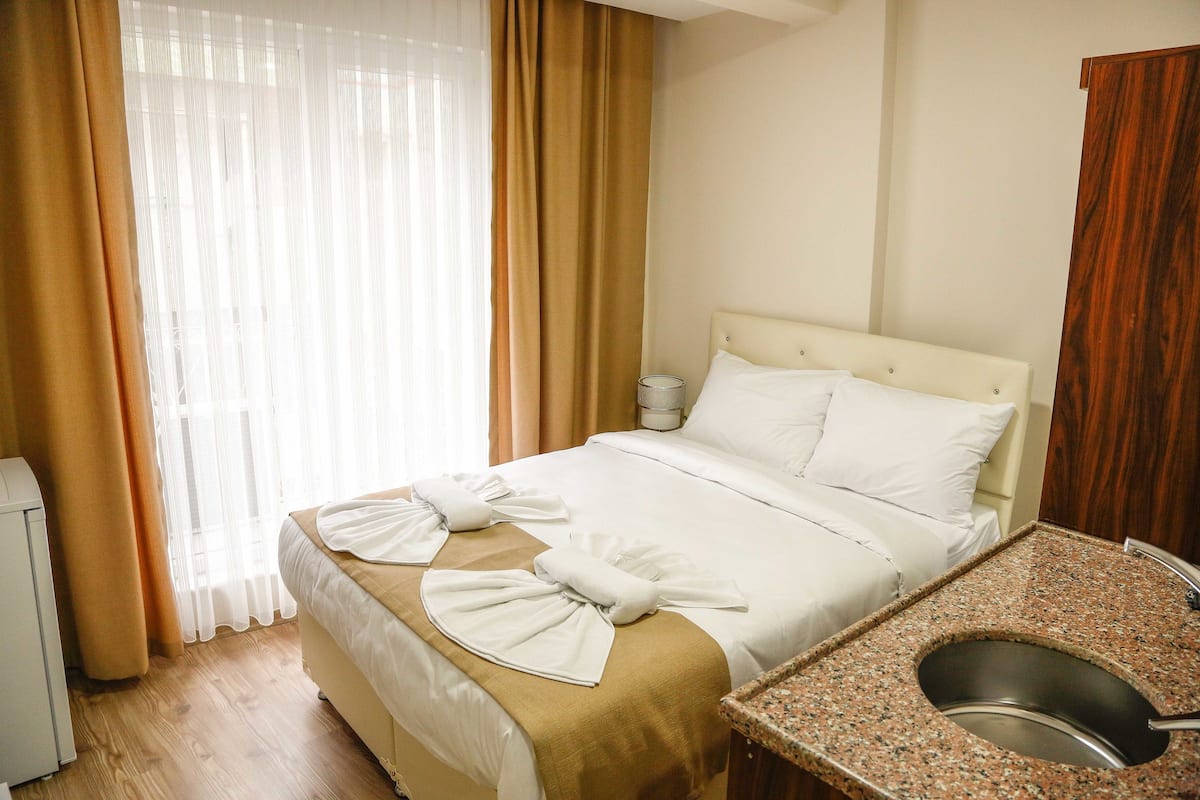 A hotel room with a bed, a bathroom with a sink, and a window with curtains.
