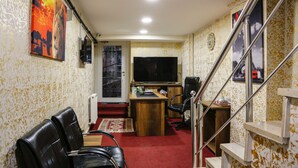 Una habitación con escritorio, dos sillas, televisor y una escalera.