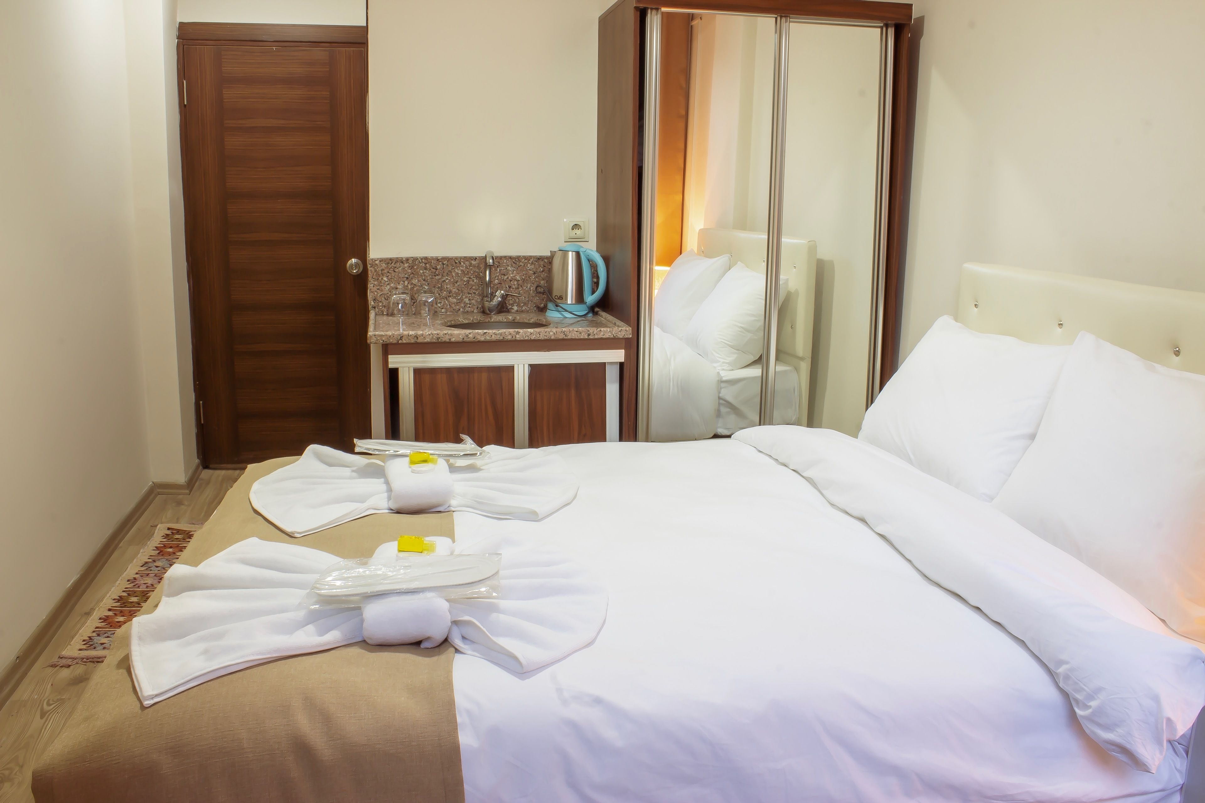 A hotel room with a bed, a bathroom, a minibar, and a mirror.