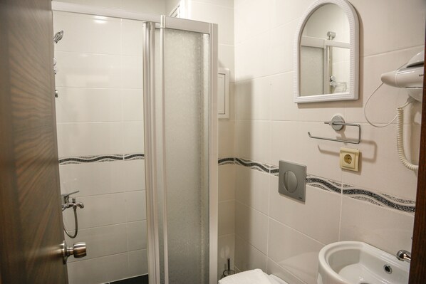 A bathroom with a shower, a sink, a mirror, and a hairdryer.