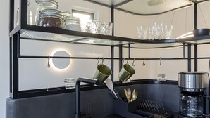 Une cuisine moderne dotée d’un évier encastré, d’étagères en métal noir et de présentoirs à verres.