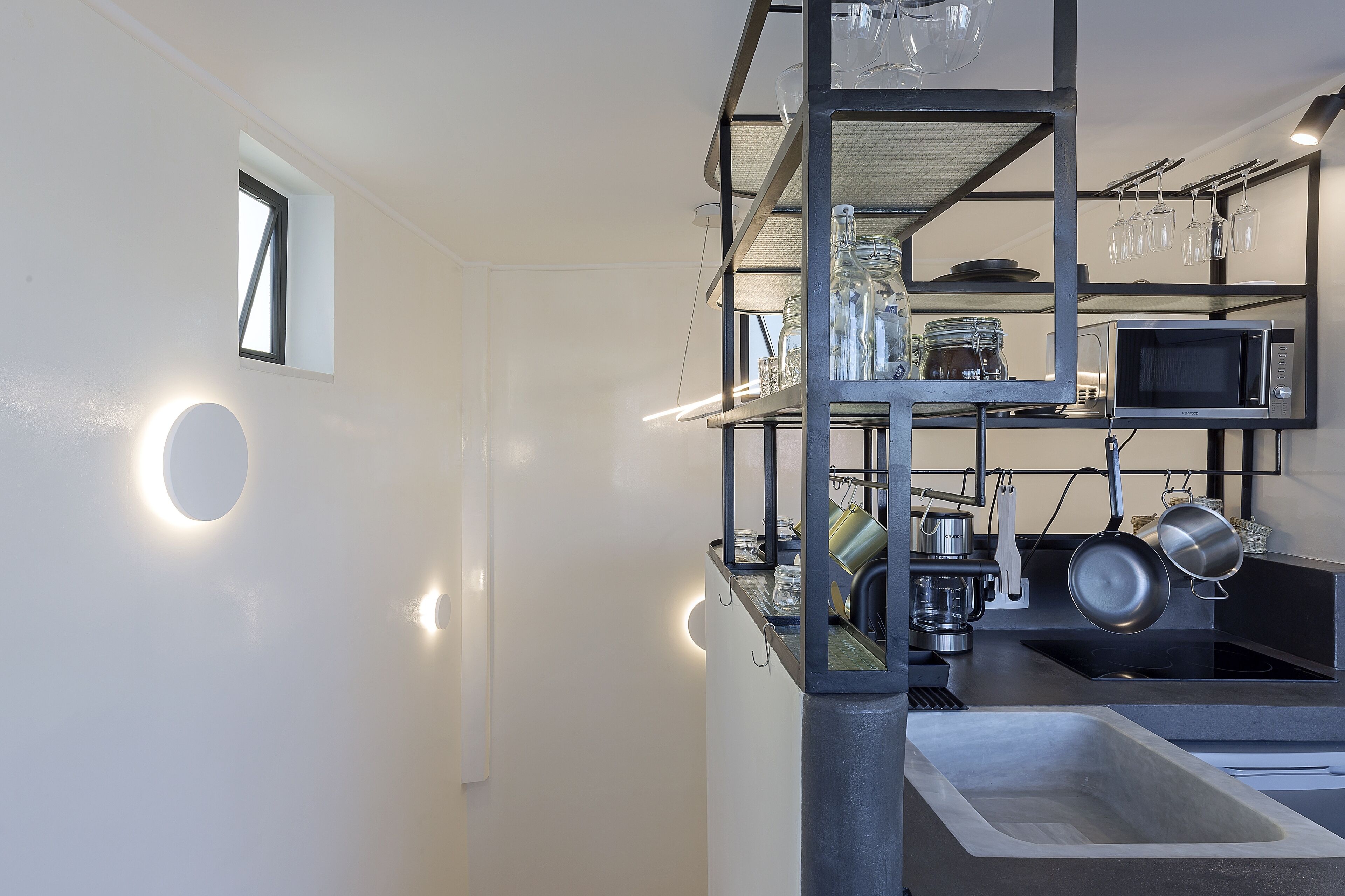 A modern kitchen with built-in shelves, a microwave, and a sink.