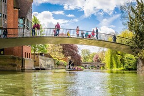 A pedestrian bridge over a river with a boat in the water. - Cambridge Bed and Breakfast (Cambridge)