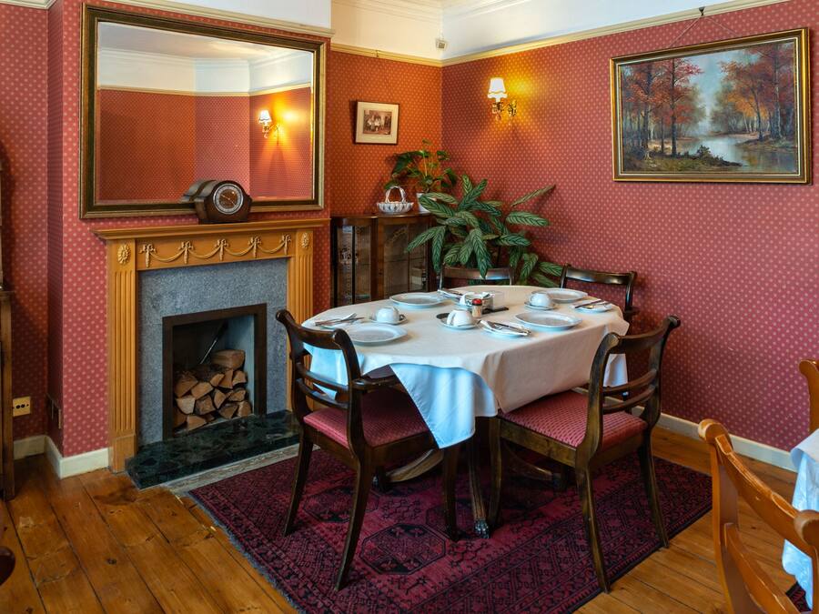 A dining area with a fireplace, a table set for four, and a large mirror above the fireplace.