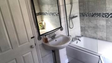 Ein Badezimmer mit Waschbecken, Spiegel, Dusche und Badewanne.