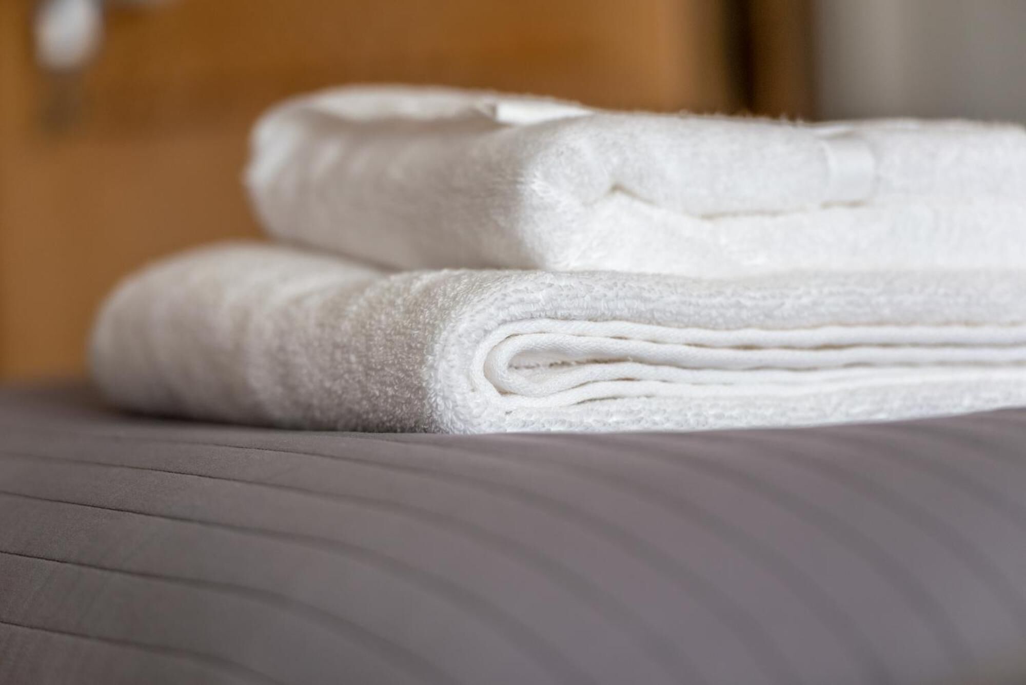 A stack of white towels on a bed with a textured gray mattress.