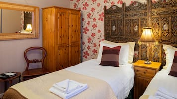 Una habitación de hotel con una cama grande, un armario de madera, un espejo y un cabecero decorativo.