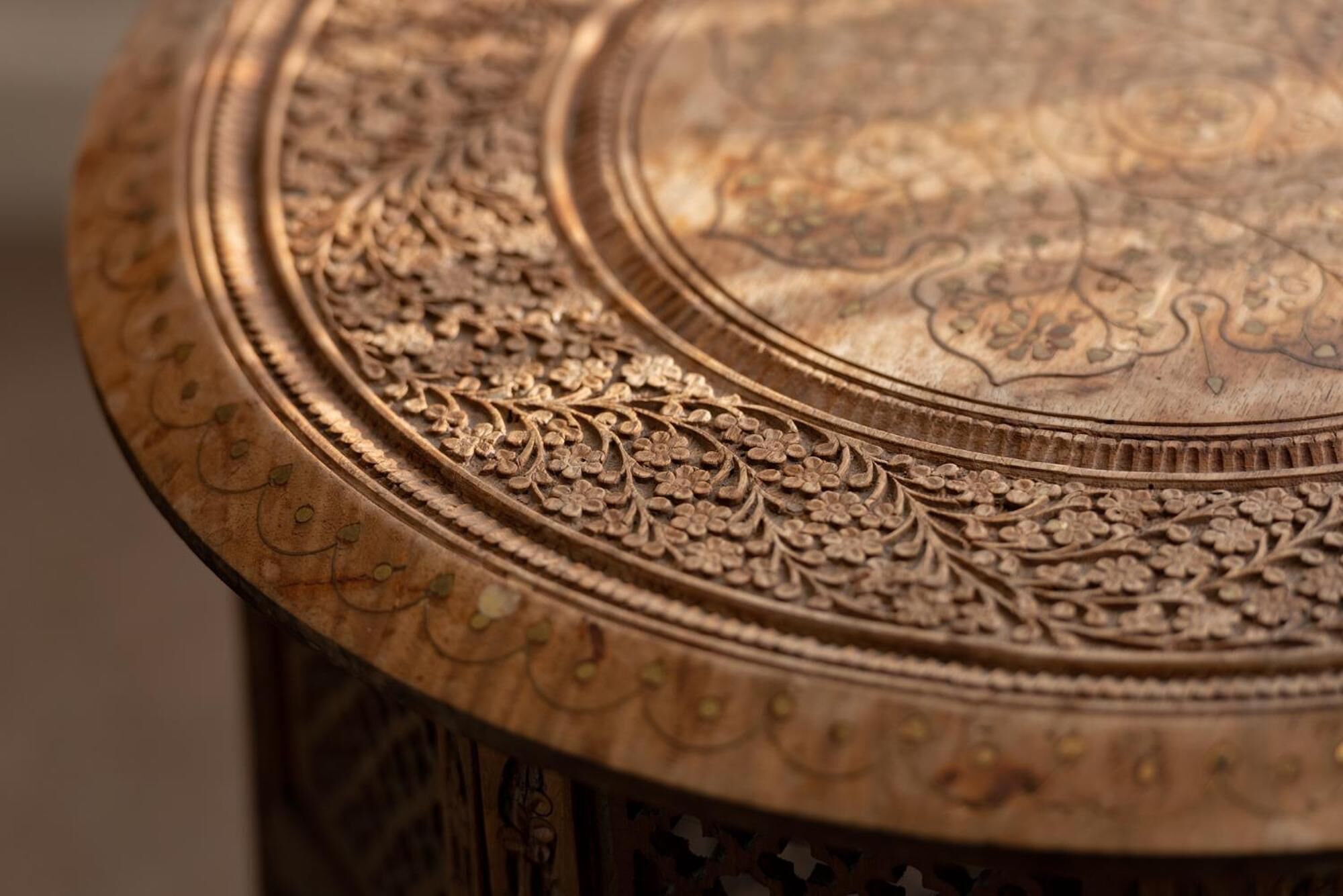 A close-up of a wooden surface with intricate floral carvings and a circular design.