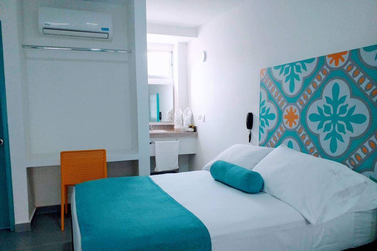Ein Hotelzimmer mit Bett, Stuhl, Badezimmer und Telefon an der Wand.