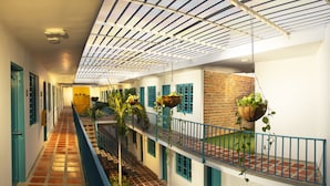 A corridor with a tiled floor, hanging plants, and a brick wall.