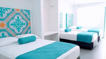 Quarto de hotel com três camas, cada uma com colcha e travesseiros azuis-esverdeados. O quarto tem um design moderno, com paredes brancas e uma grande janela.