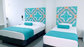 Dos camas individuales con ropa de cama azul verdosa y blanca, un papel tapiz estampado y un teléfono en la pared.