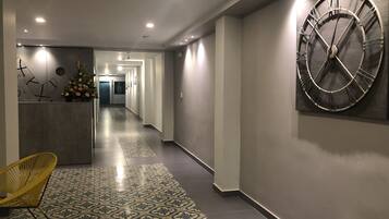 En hall med en stor väggklocka, en receptionsdisk och ett mönstrat golv.
