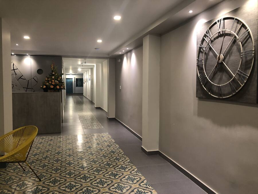 En hall med en stor väggklocka, en receptionsdisk och ett mönstrat golv.