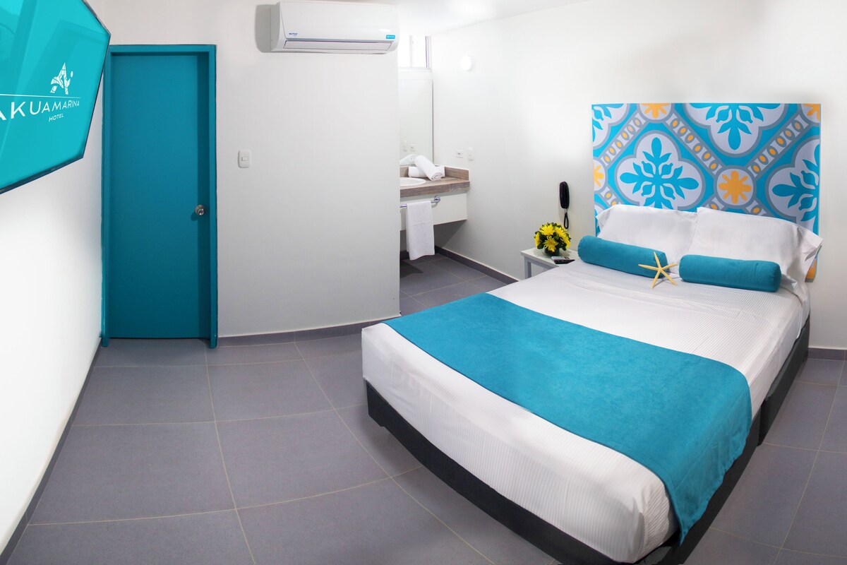 A hotel room with a bed, a bathroom, and a chair.