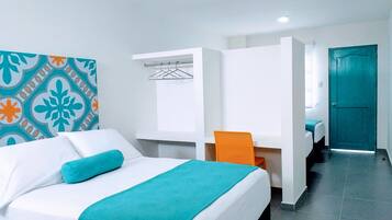 A hotel room with a bed, a chair, a wardrobe, and a door.
