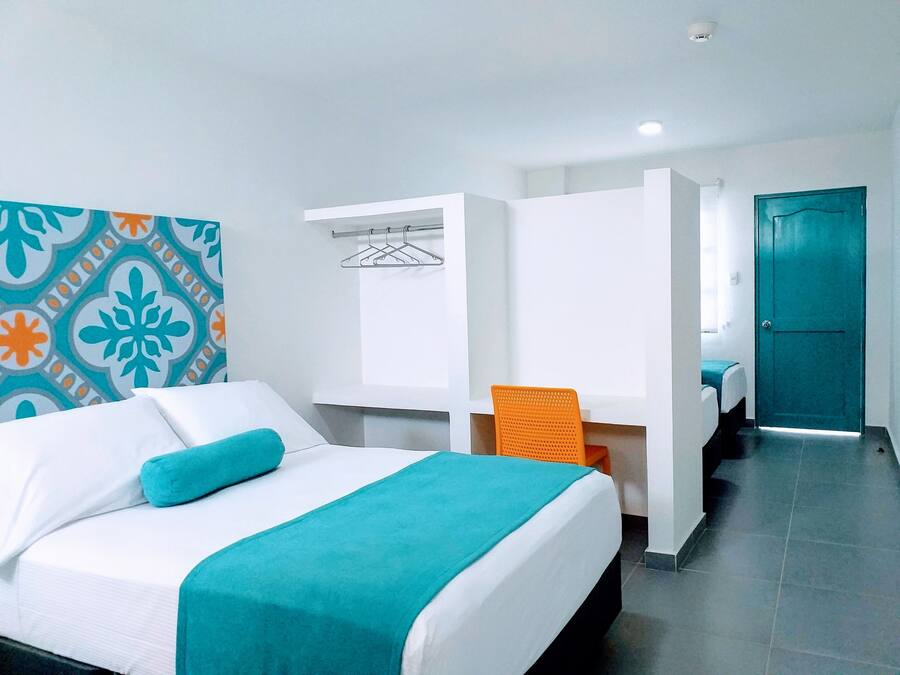 A hotel room with a bed, a chair, a wardrobe, and a door.