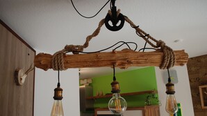 Un plafond en bois rustique, avec des cordes apparentes et trois ampoules suspendues.