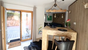 Une cuisine moderne avec un plan de travail en bois, des chaises noires et un luminaire suspendu.