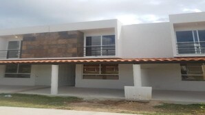 Um edifício moderno de dois andares com telhado plano, janelas amplas e área de varanda coberta.