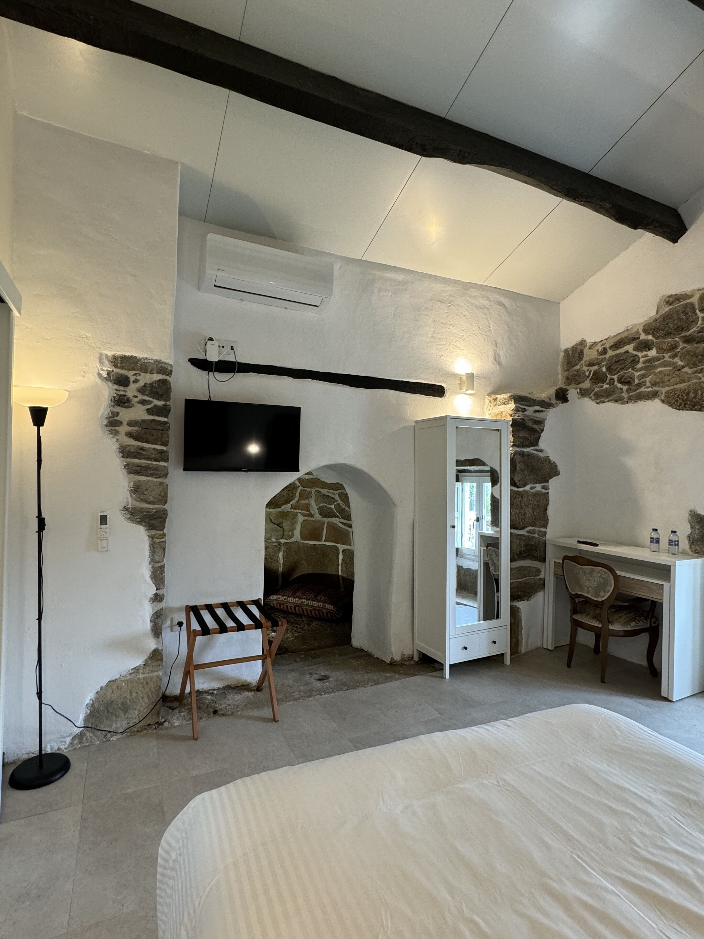 A bedroom with a stone fireplace, a bed, a desk, and a chair.