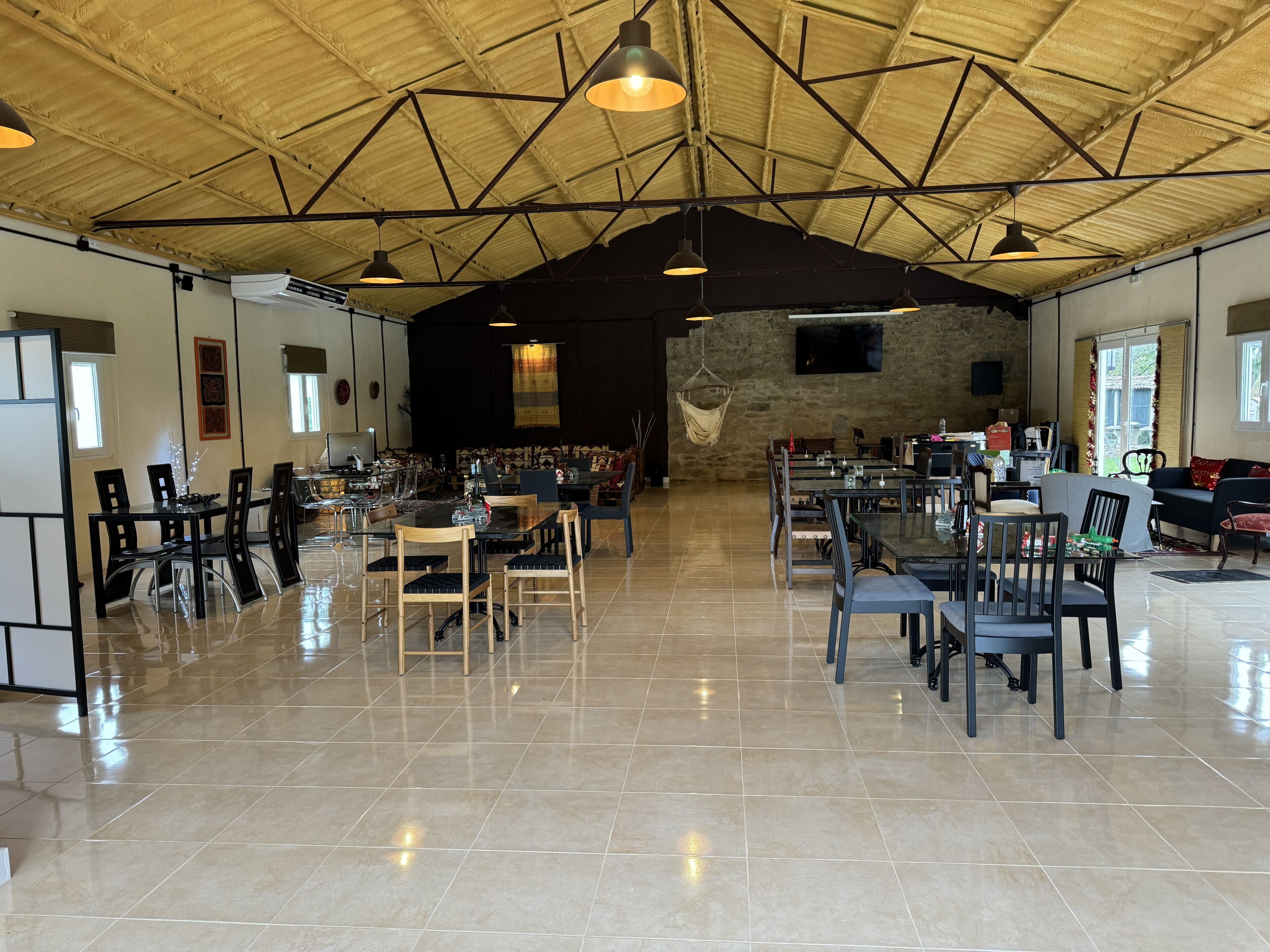 Un vaste espace dédié à la salle à manger, doté de hauts plafonds et d’un éclairage moderne. Des tables et des chaises y sont disposées pour les repas.