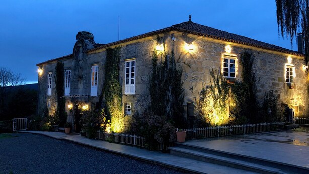 Un edificio de piedra con numerosas ventanas, algunas con contraventanas, y un techo de tejas.