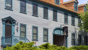 Un edificio histórico con fachada azul, numerosas ventanas y una entrada destacada con un letrero.