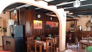 A restaurant with wooden furniture, a refrigerator, and wall art. - Hotel El Nevado Malargüe (Malargüe)