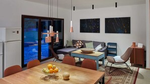 A modern living room with a wooden dining table, a sofa, and a coffee table. There is a large window with a view of a pool. - Holiday house GARICA with spacious garden (Garica)