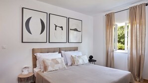 A bedroom with a bed, pillows, a bedside table, and a window with curtains. - Holiday house GARICA with spacious garden (Garica)