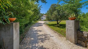 A gravel pathway leading to a house surrounded by lush greenery and trees. - Holiday house GARICA with spacious garden (Garica)