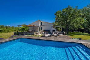 Une piscine avec des chaises longues et un espace patio couvert.