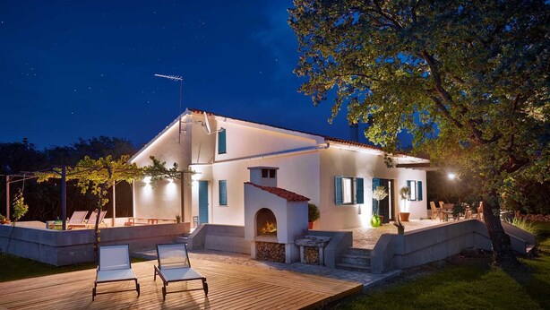 A two-story house with a wooden deck, outdoor seating, and a fire feature. - Holiday house GARICA with spacious garden (Garica)