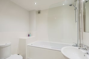 A modern bathroom with a glass-enclosed shower, a white bathtub, and a sink.