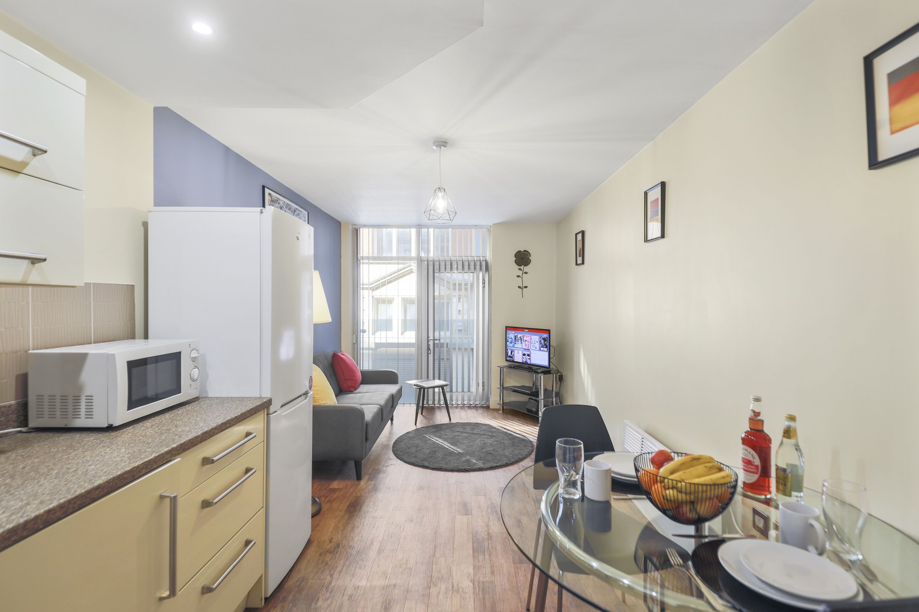 Een compacte leefruimte met een kitchenette, een eethoek en een zithoek met een televisie.