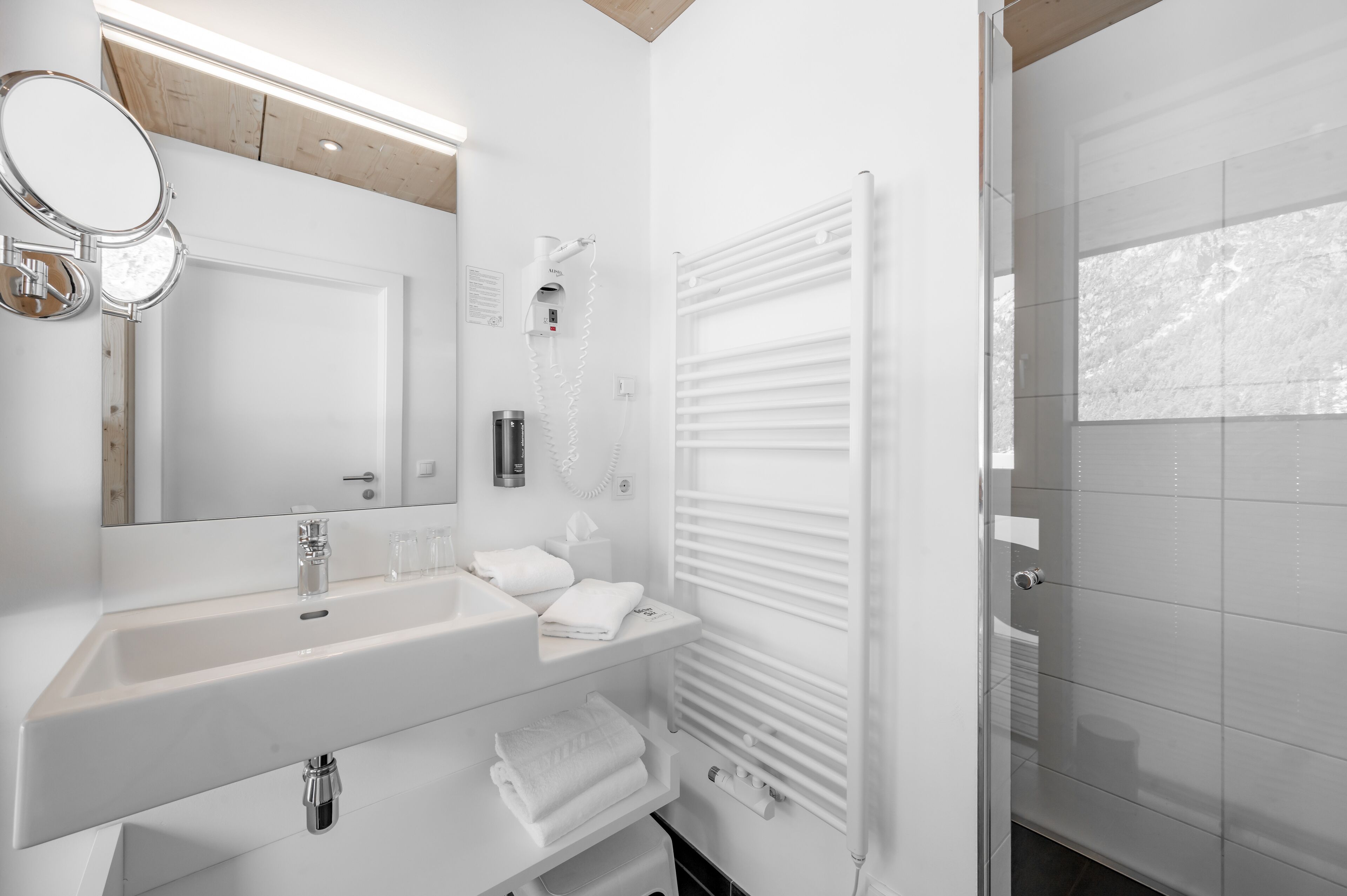 A modern bathroom with a white sink, mirror, and towel rack.