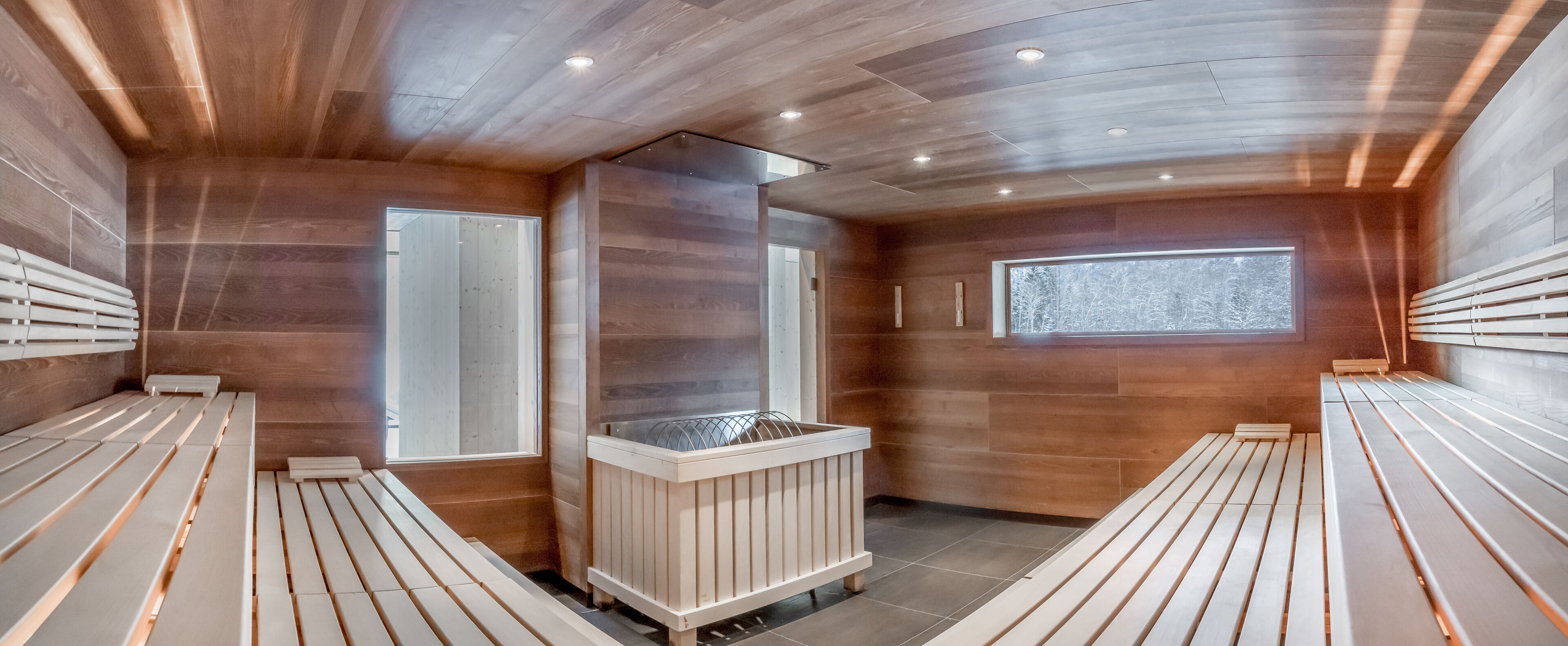 Un sauna con bancos de madera y una unidad de calefacción central.