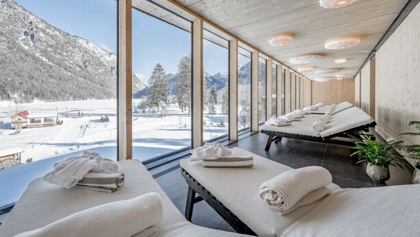 A spa room with large windows, wooden ceiling, and massage tables. - Hotel Fischer am See (Heiterwang)