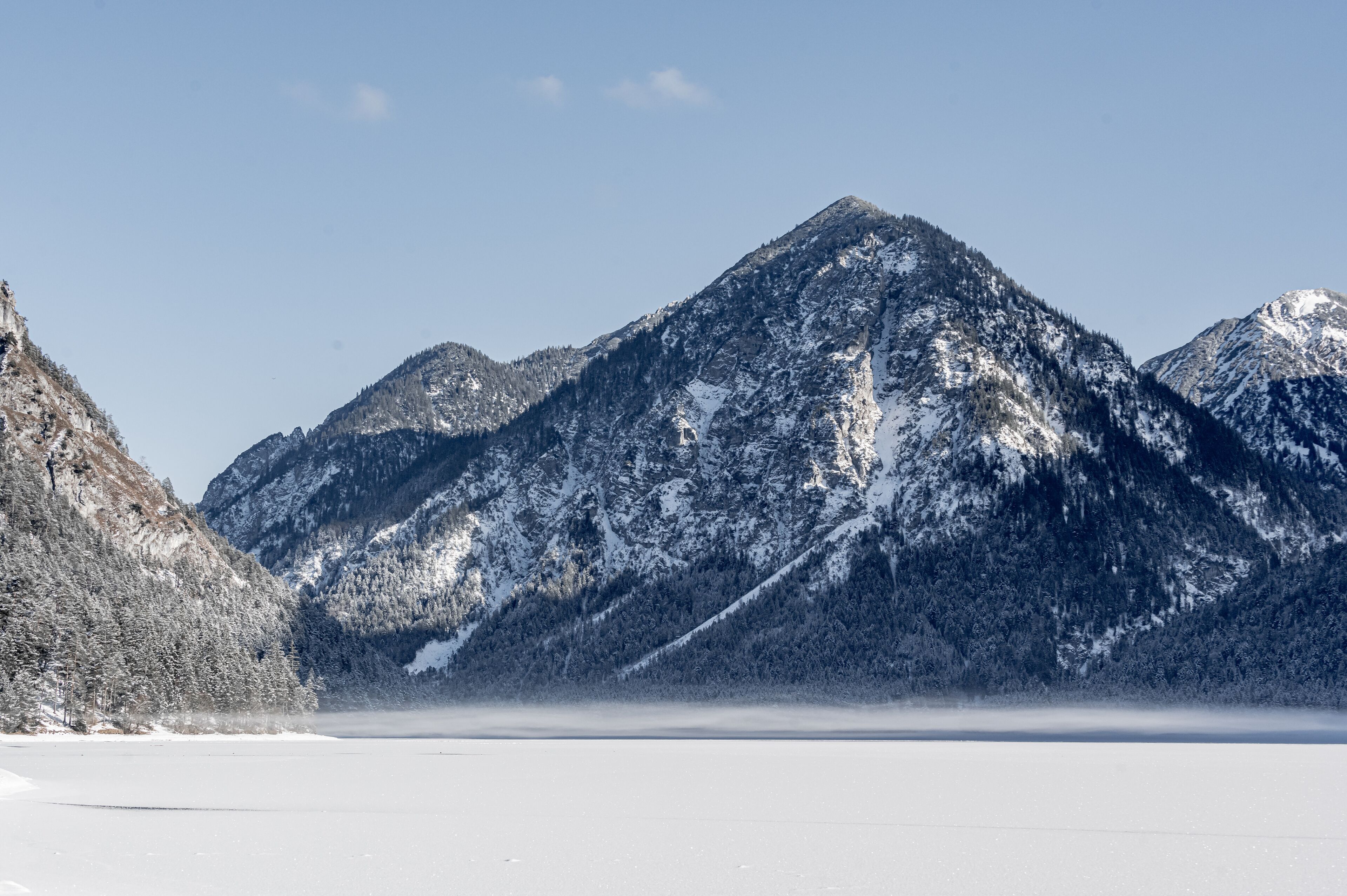 Un paisaje montañoso cubierto de nieve con cielo despejado.