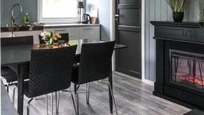 A modern kitchen with a dining area, a black stove, and a window with a view of greenery.