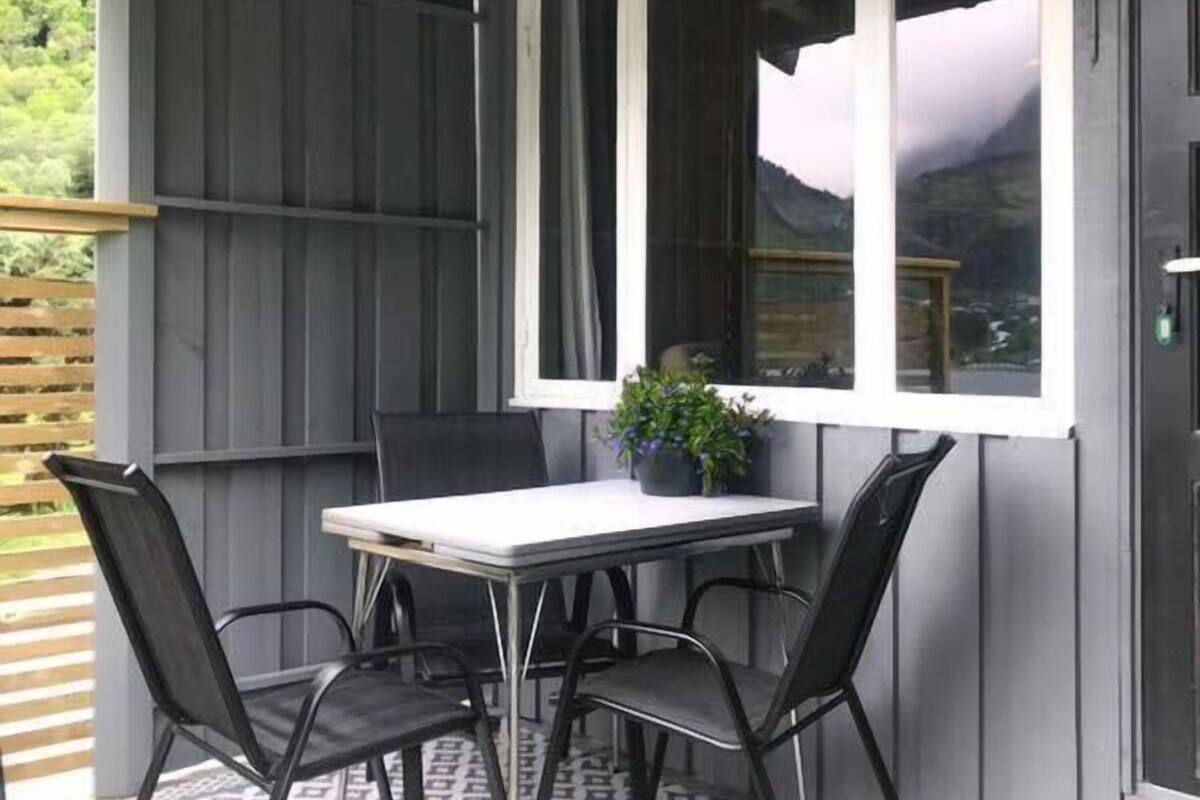 A covered outdoor seating area with a table and chairs, a potted plant, and a view of the outdoors.