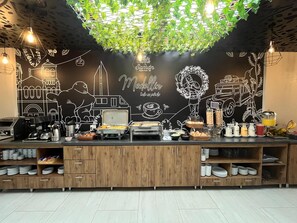 Un comptoir de restaurant avec un mur recouvert d’un tableau noir, divers plats proposés et une machine à café.