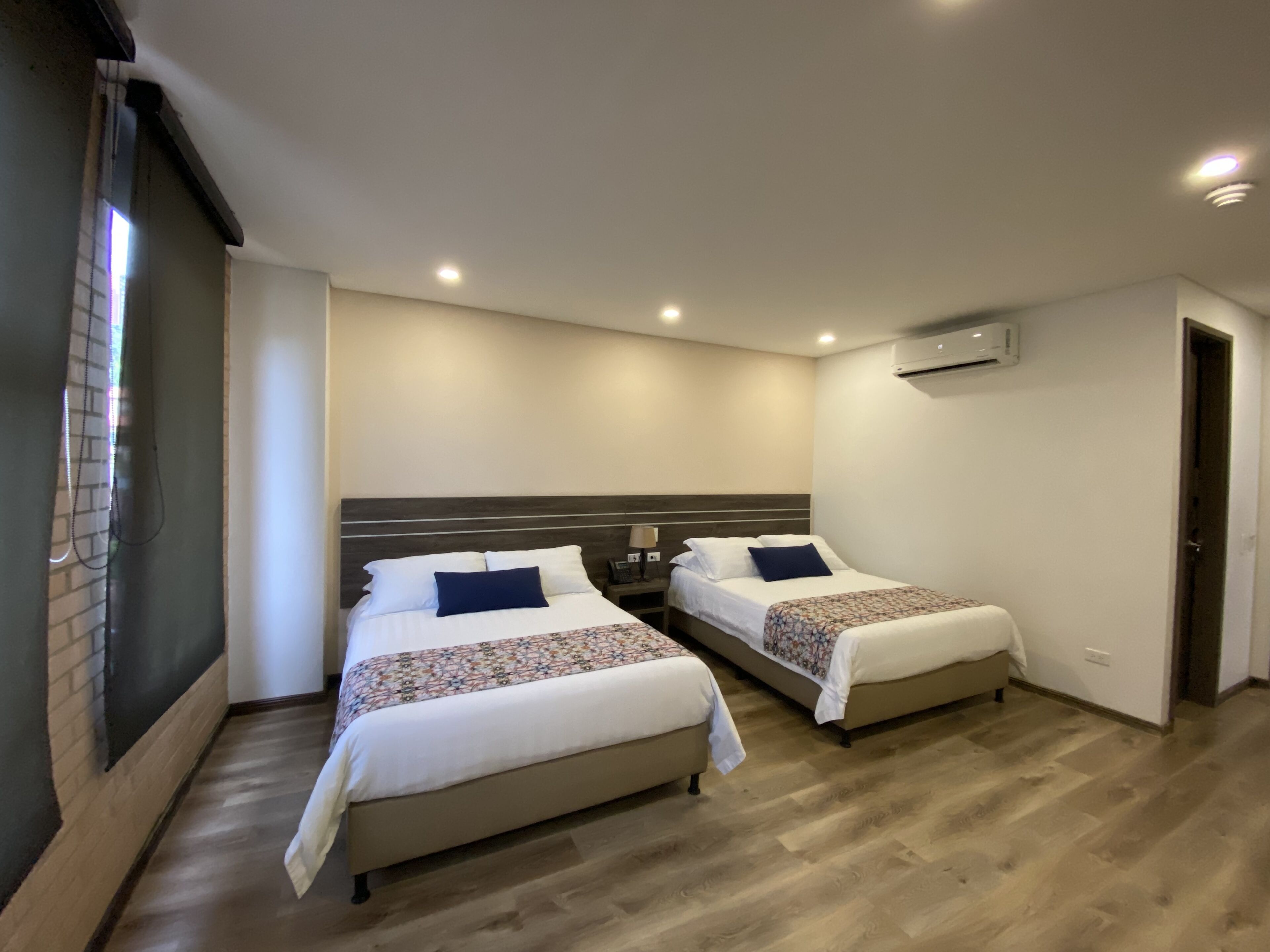 A hotel room with two beds, a brick wall, and a wooden floor.