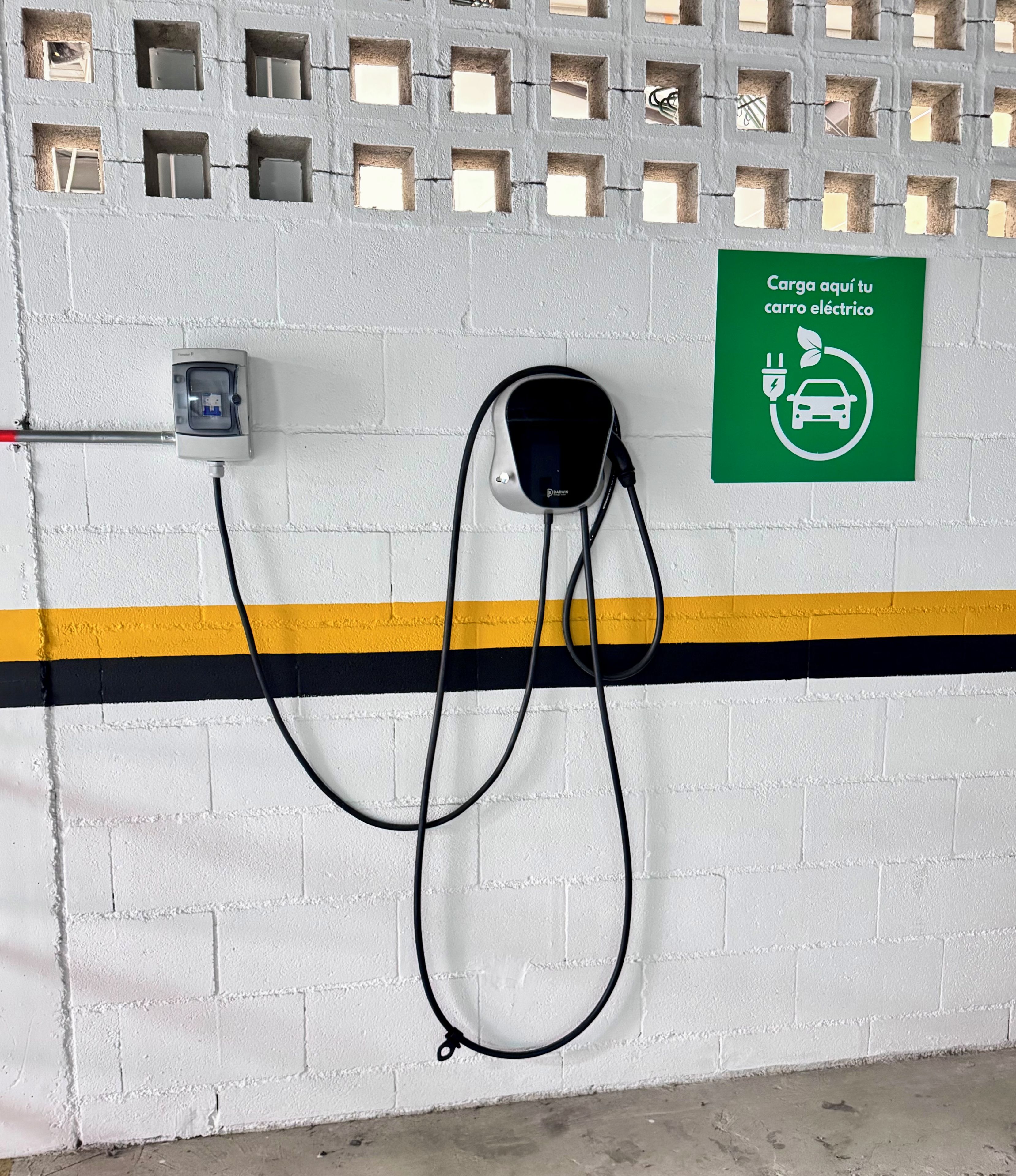A wall-mounted electric vehicle charging station with a green sign indicating it is for electric cars.