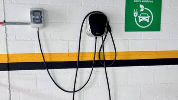 A wall-mounted electric vehicle charging station with a green sign indicating it is for electric cars.